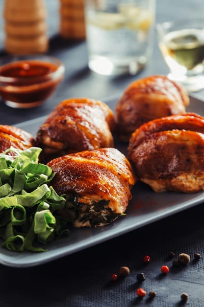 Bacon-wrapped stuffed chicken thighs on a dark plate